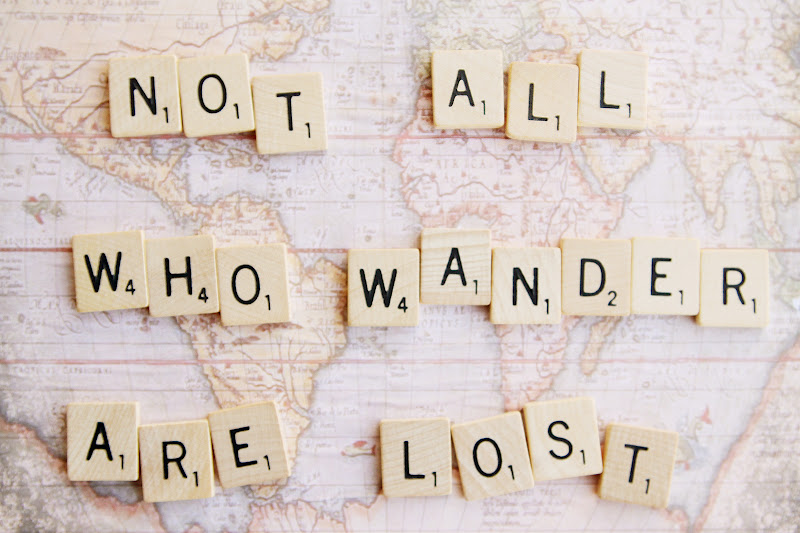 A world map with scrabble tiles spelling out, 'Not all who wander are lost.''